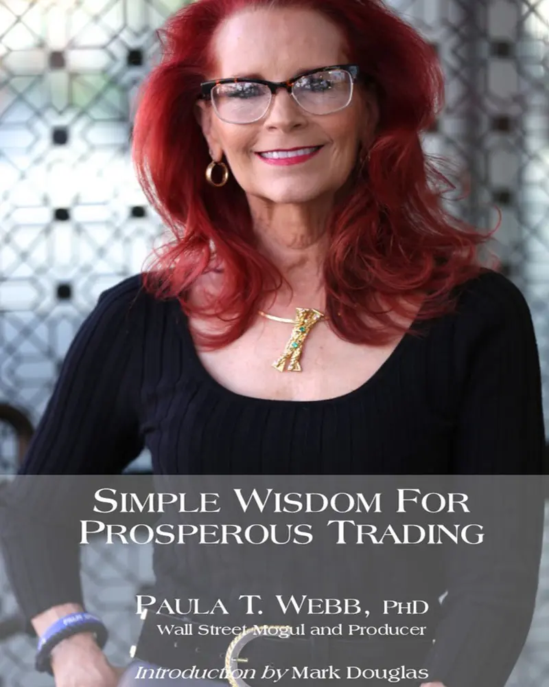 A woman with red hair and glasses is holding a book.