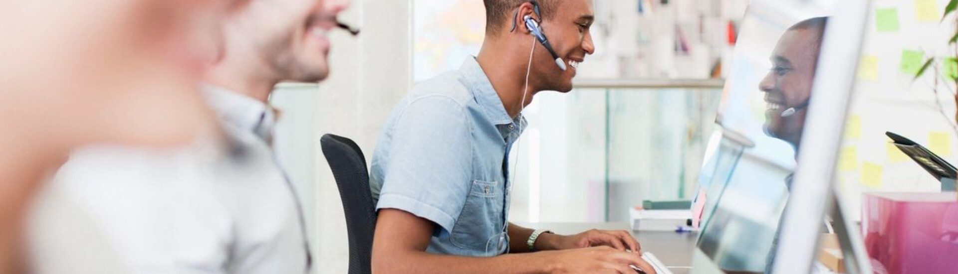 A man with headphones on sitting at his desk.