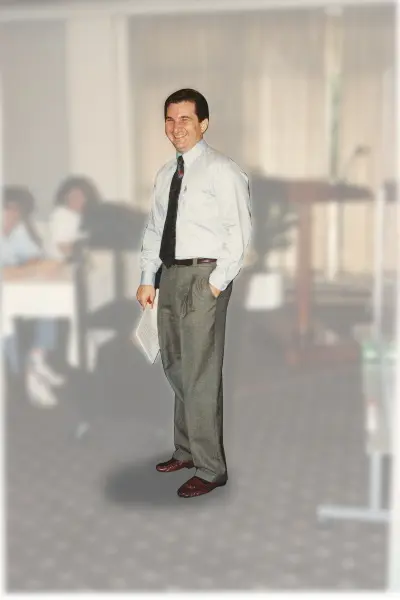 A man in dress clothes standing next to a table.