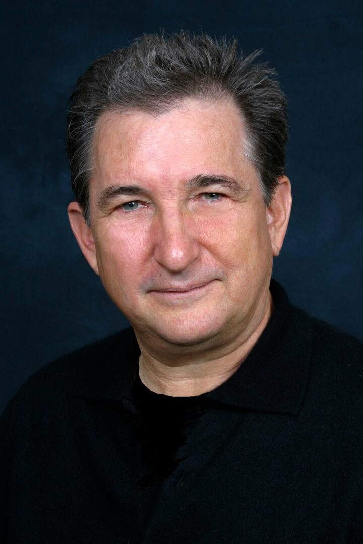 A man with short hair and a black shirt.